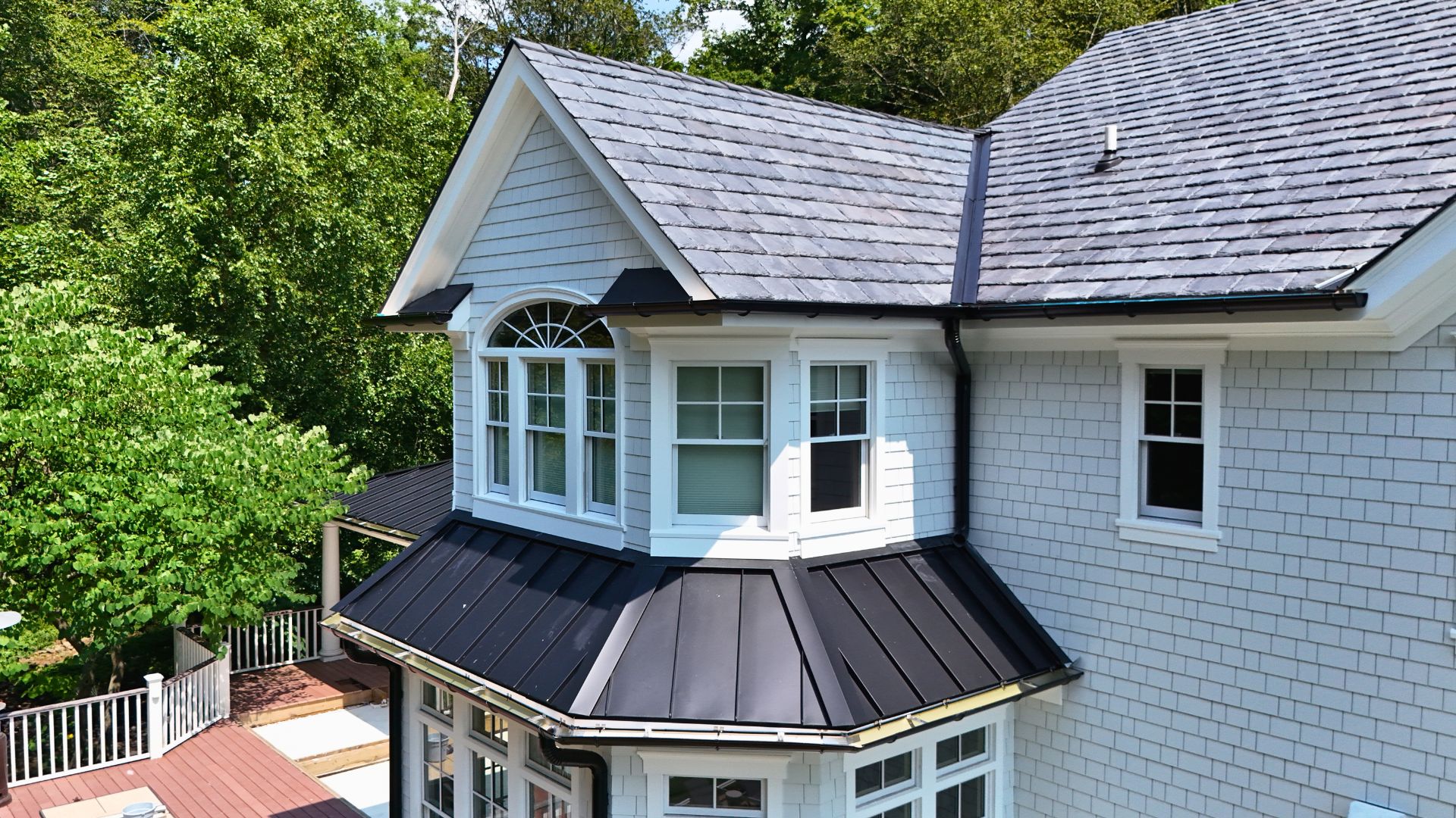 Brava synthetic slate roof, black standing seam metal roof, and James Hardie siding installed on a home